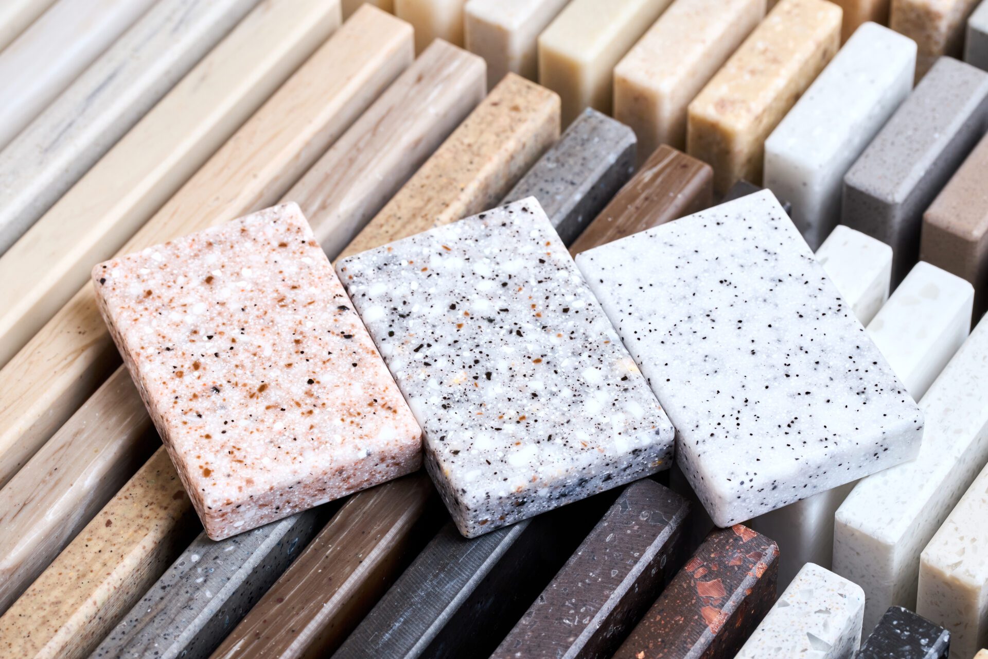 Porcelain three stoneware square samples laid on kitchen countertop examples of future kitchen fasade exterior. Samples slabs of natural granite marble quartz for stone countertops close up. Porcelain three stoneware square samples laid on kitchen countertop examples of future kitchen fasade exterior. Samples slabs of natural granite marble quartz for stone countertops close up.