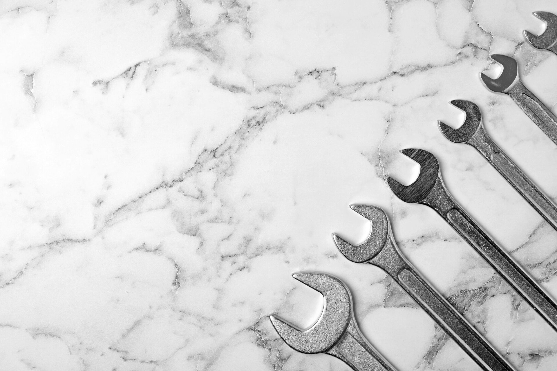 New wrenches on marble background, top view with space for text. Plumber tools New wrenches on marble background, top view with space for text. Plumber tools